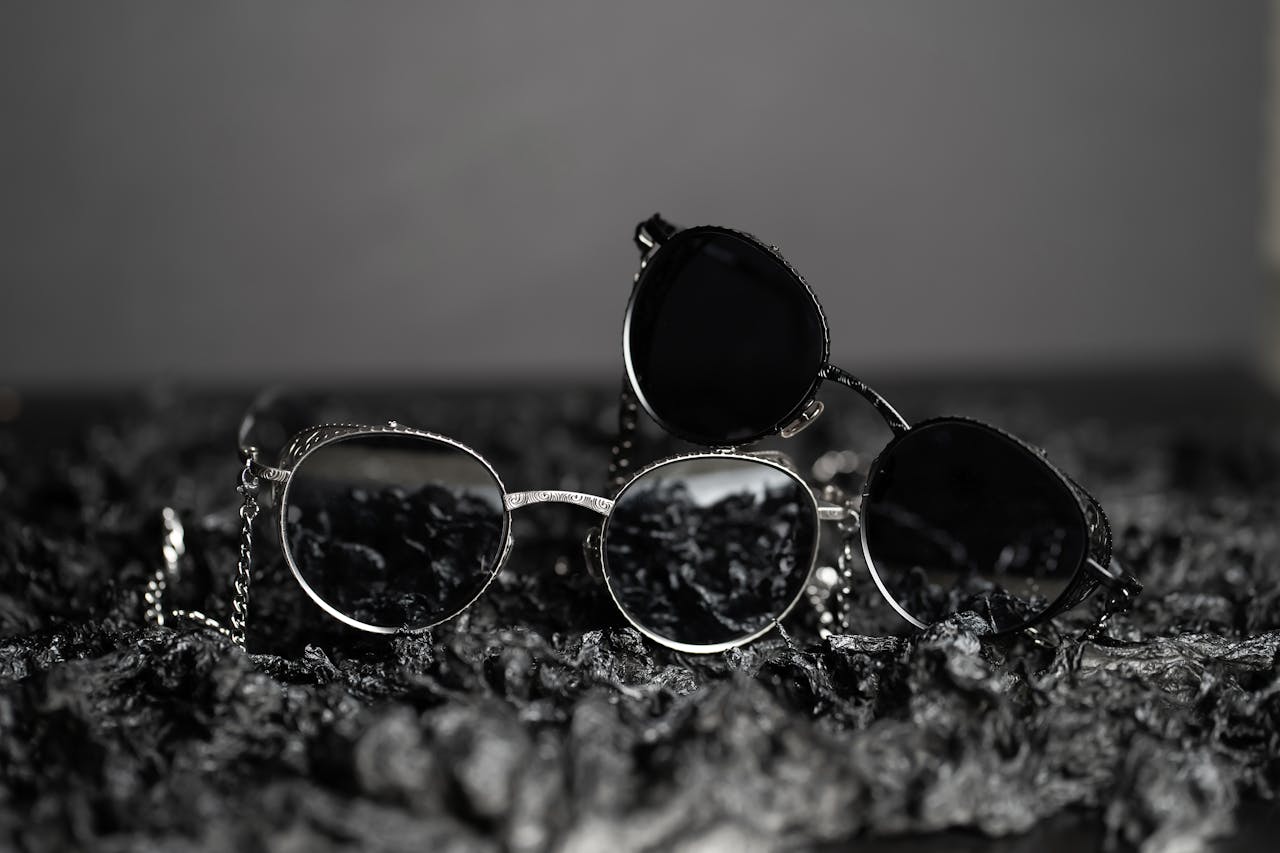Three black and white sunglasses arranged on a textured dark surface, emphasizing elegance and style.