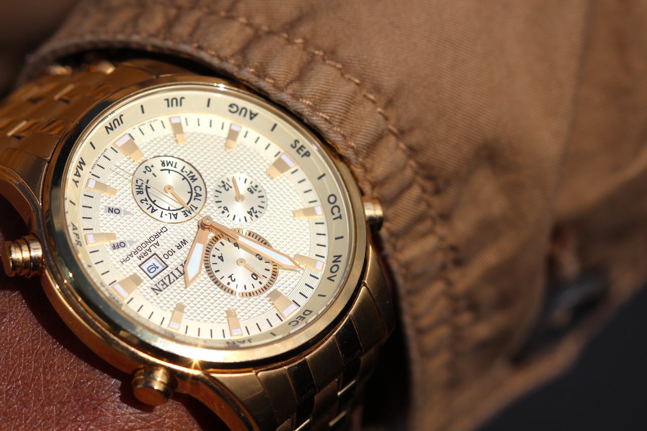 menu-03 Close-up of a sophisticated gold wristwatch with functional chronograph and date display.