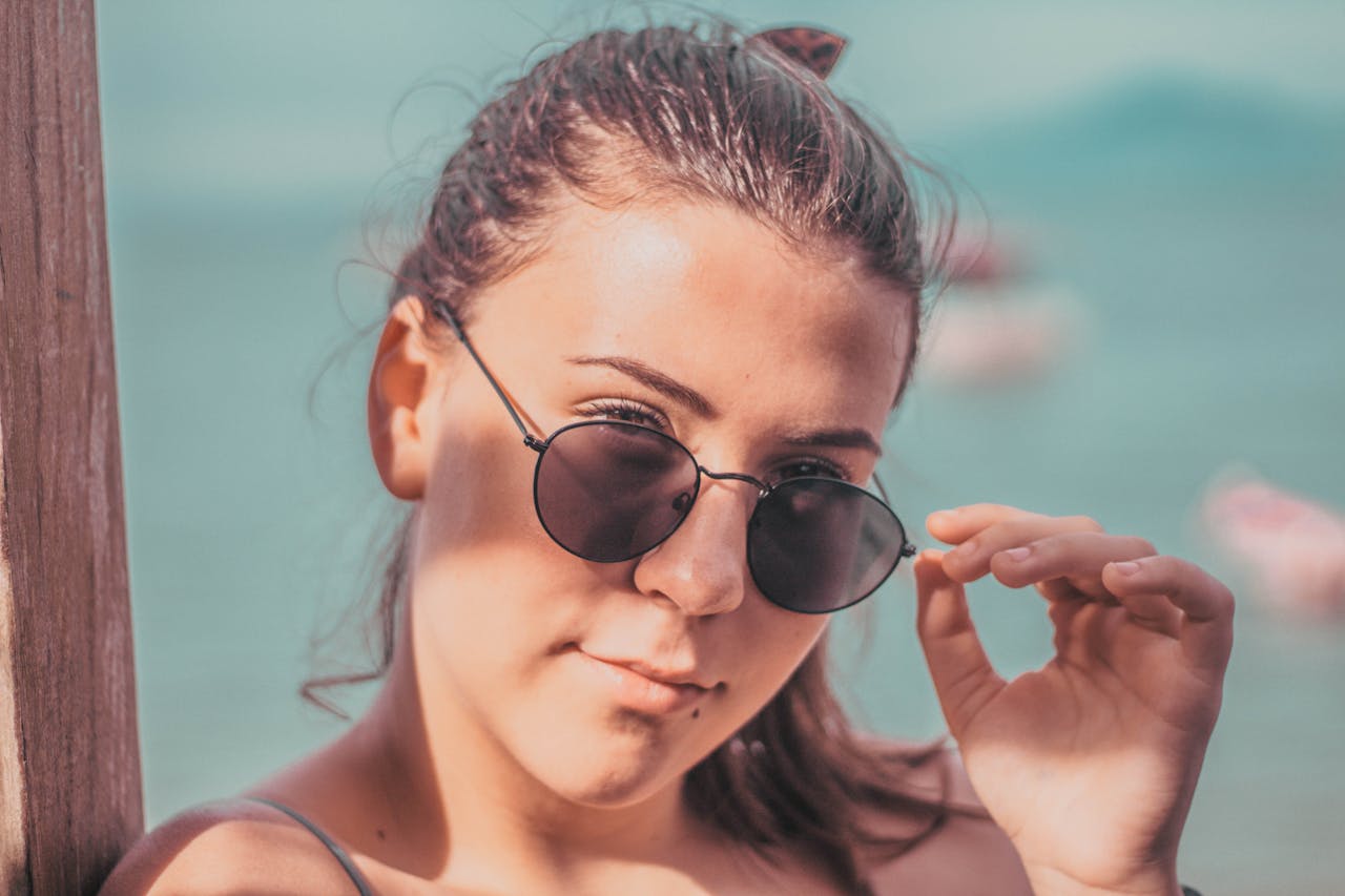 Portrait of a young woman wearing sunglasses enjoying sunny weather outdoors.