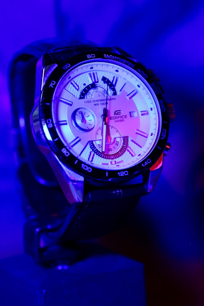 menu-08 Close-up of a luxury watch with mixed vibrant lighting, highlighting its intricate details.