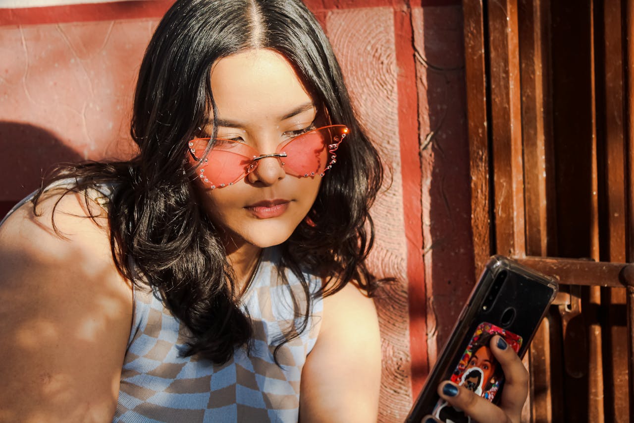 menu-01 Young woman with sunglasses takes a selfie, enjoying sunny outdoor vibes.